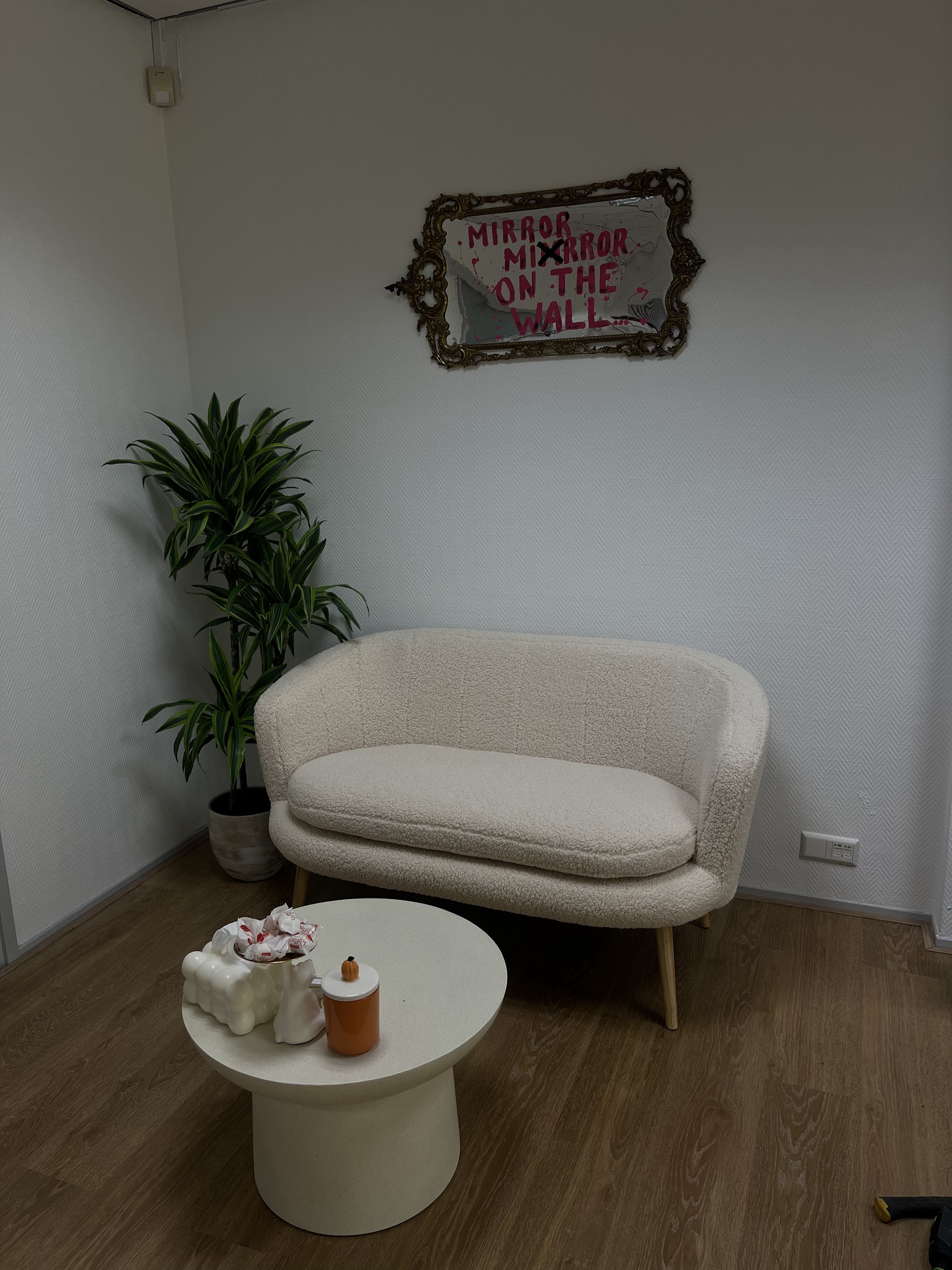 Cremekleurige boucle bank met een plant en een rond bijzettafeltje