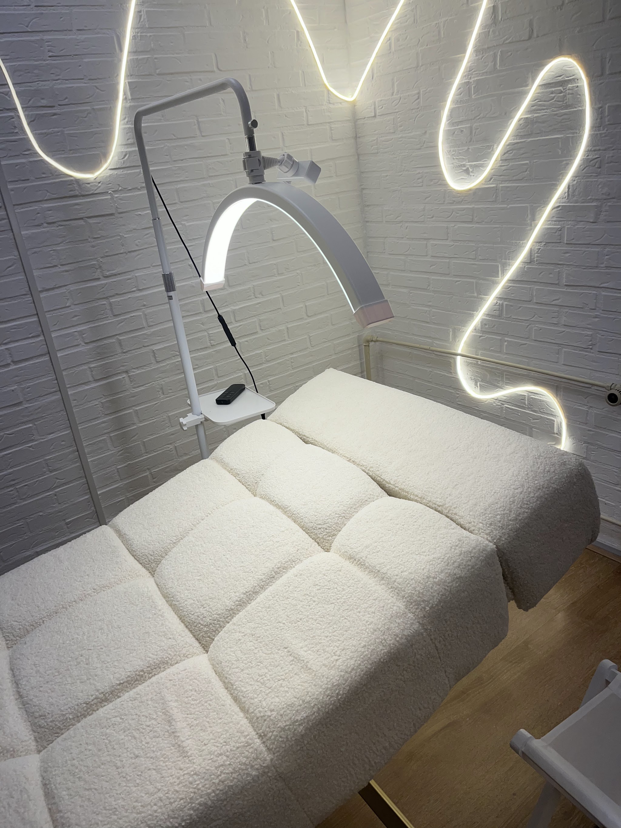 Het behandelbed met de ledlamp en het neonlicht op de muur in de salon